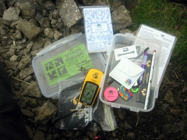 The contents of a geocache with a gps receiver at hand.